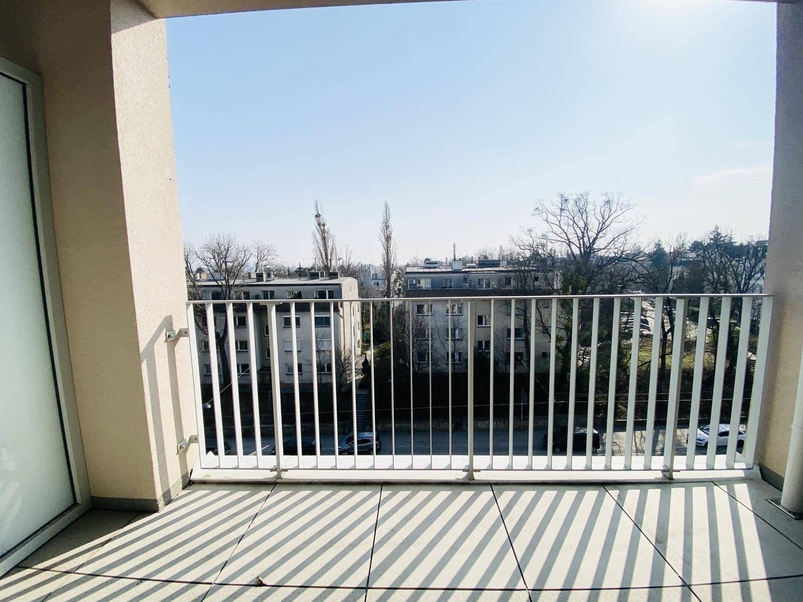 Geräumiger Balkon mit Metallgeländer und weitem Blick über die Stadt.