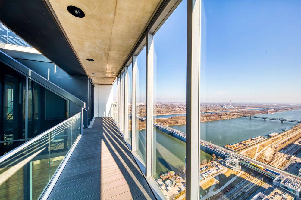 Langer Balkon mit Glasgeländer und beeindruckendem Panoramablick auf die Stadt und den Fluss.