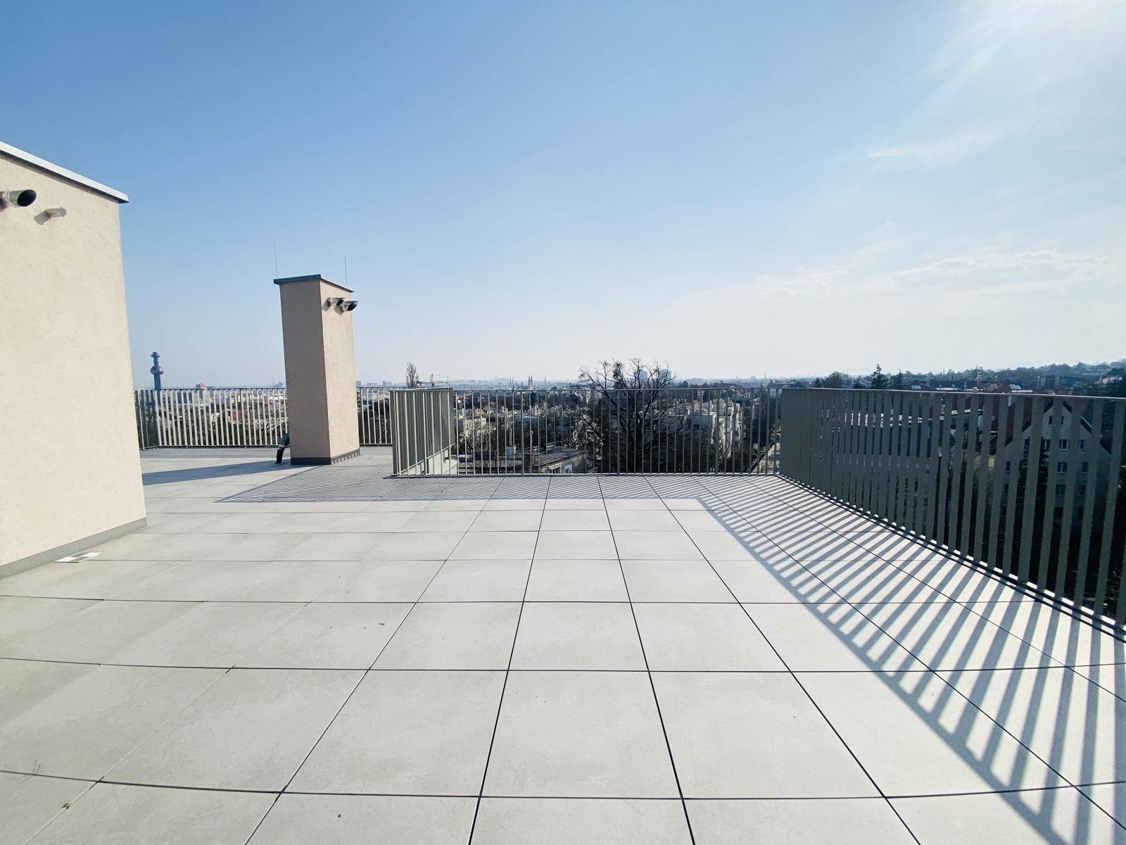 Weitläufige Dachterrasse mit Fliesenboden und Panoramablick über die Stadt und die Umgebung.