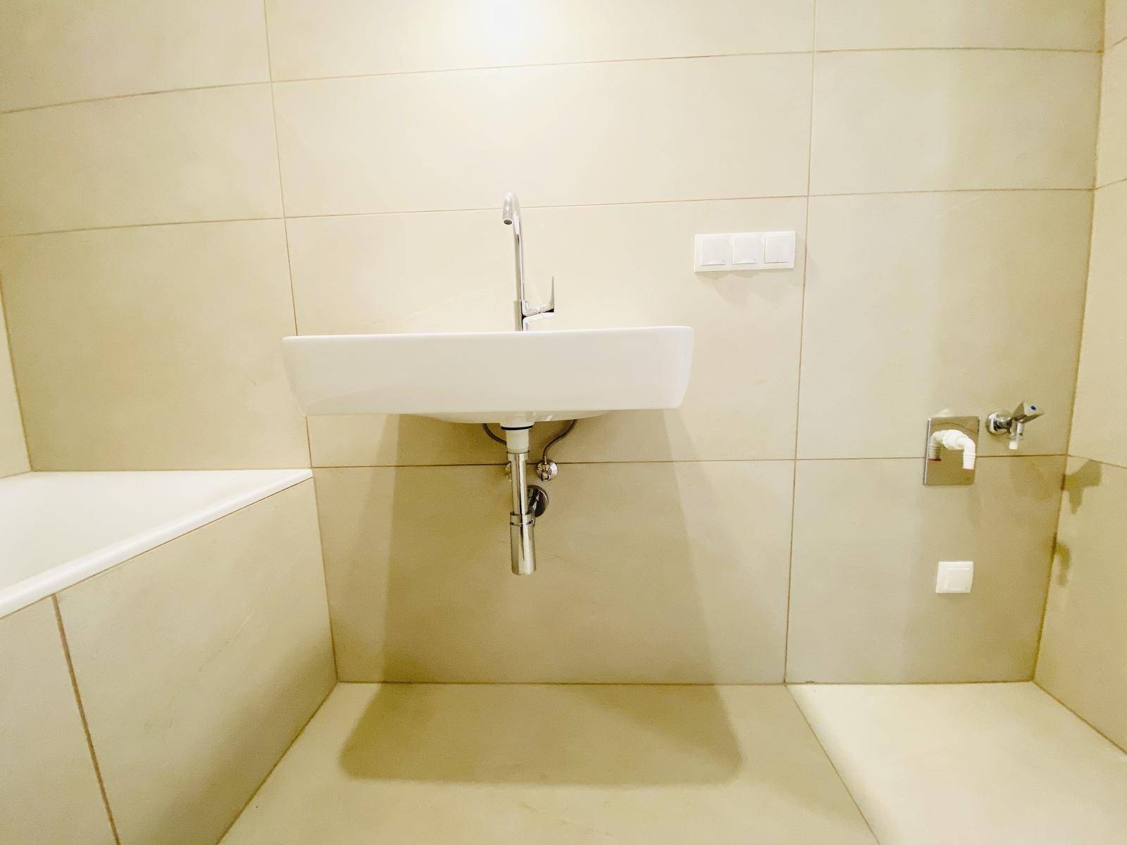 Detailansicht des modernen Badezimmers mit Waschbecken und beigefarbenen Fliesen.