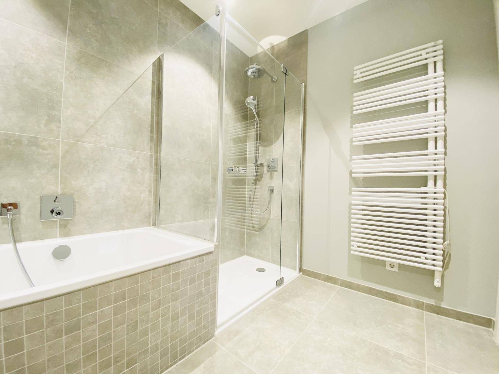 Elegantes Badezimmer mit Badewanne, großer Duschkabine und praktischem Handtuchheizkörper.