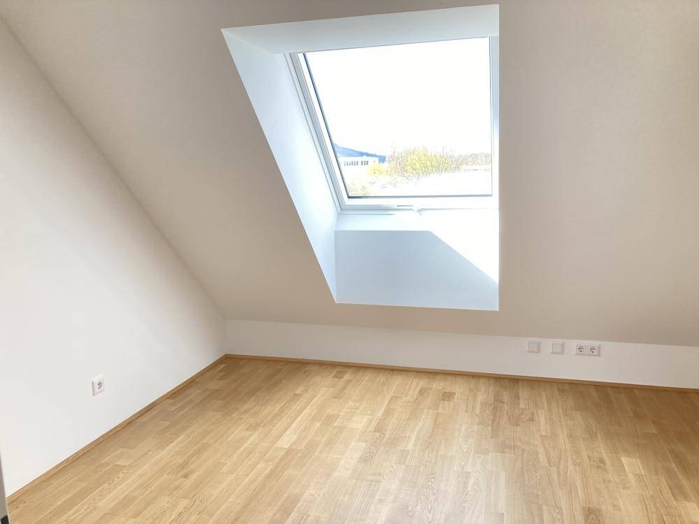 Heller Dachgeschossraum mit einem großen Dachfenster und neuem Holzboden.