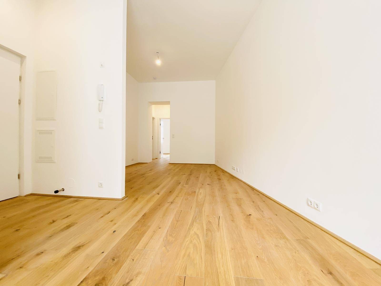 Geräumiger Wohnbereich mit Holzboden und Zugang zu weiteren Räumen.