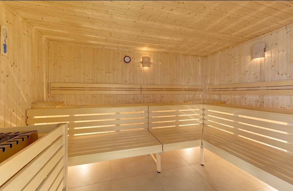 Geräumige Sauna mit hellen Holzpaneelen, mehrstufigen Bänken und traditionellem Saunaofen.