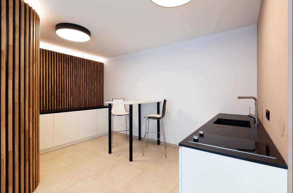 Kleine Küchenzeile mit schwarzer Arbeitsplatte, Spüle und integrierten Kochfeldern in modernem Design.