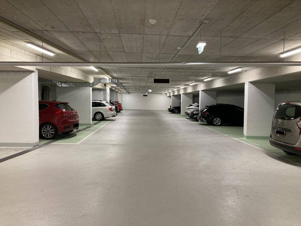 Saubere Tiefgarage mit markierten Parkplätzen und verschiedenen geparkten Fahrzeugen.