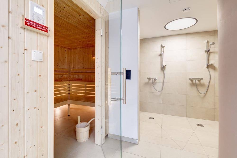 Eingang zur Sauna und angrenzende Duschbereiche mit modernen Armaturen und Fliesen.