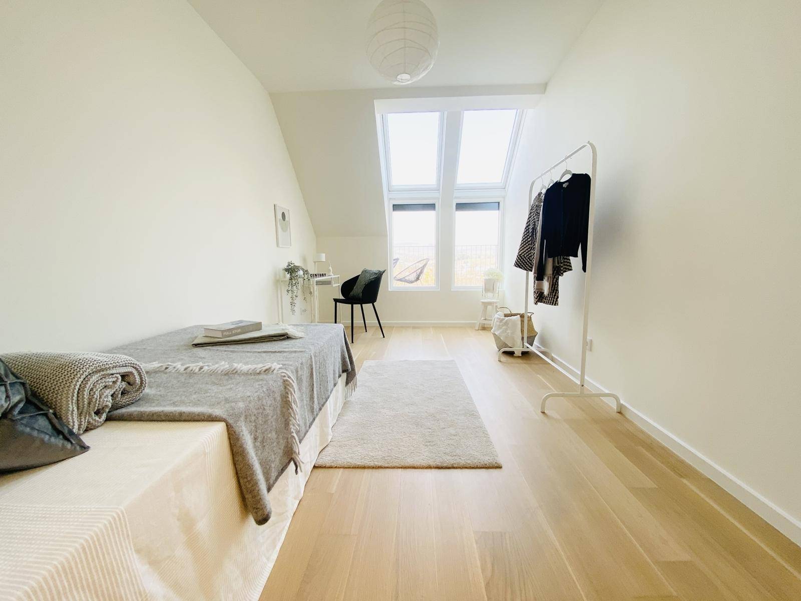 Helles Schlafzimmer mit Dachfenstern, Holzboden und minimalistischer Einrichtung für eine ruhige Atmosphäre.
