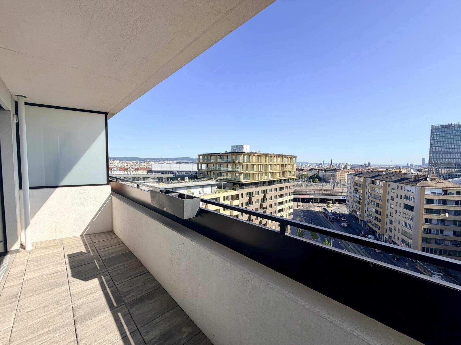 Sonniger Balkon mit Fliesenboden und Panoramablick auf die urbane Skyline.