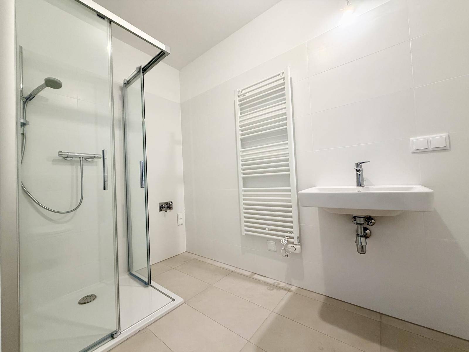 Modernes Badezimmer mit Dusche, Waschbecken und beheiztem Handtuchhalter.