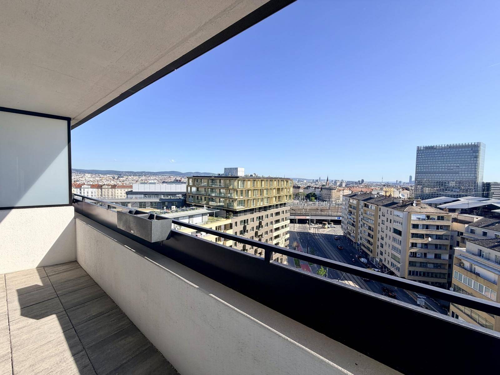 Sonniger Balkon mit Fliesenboden und Panoramablick auf die urbane Skyline.