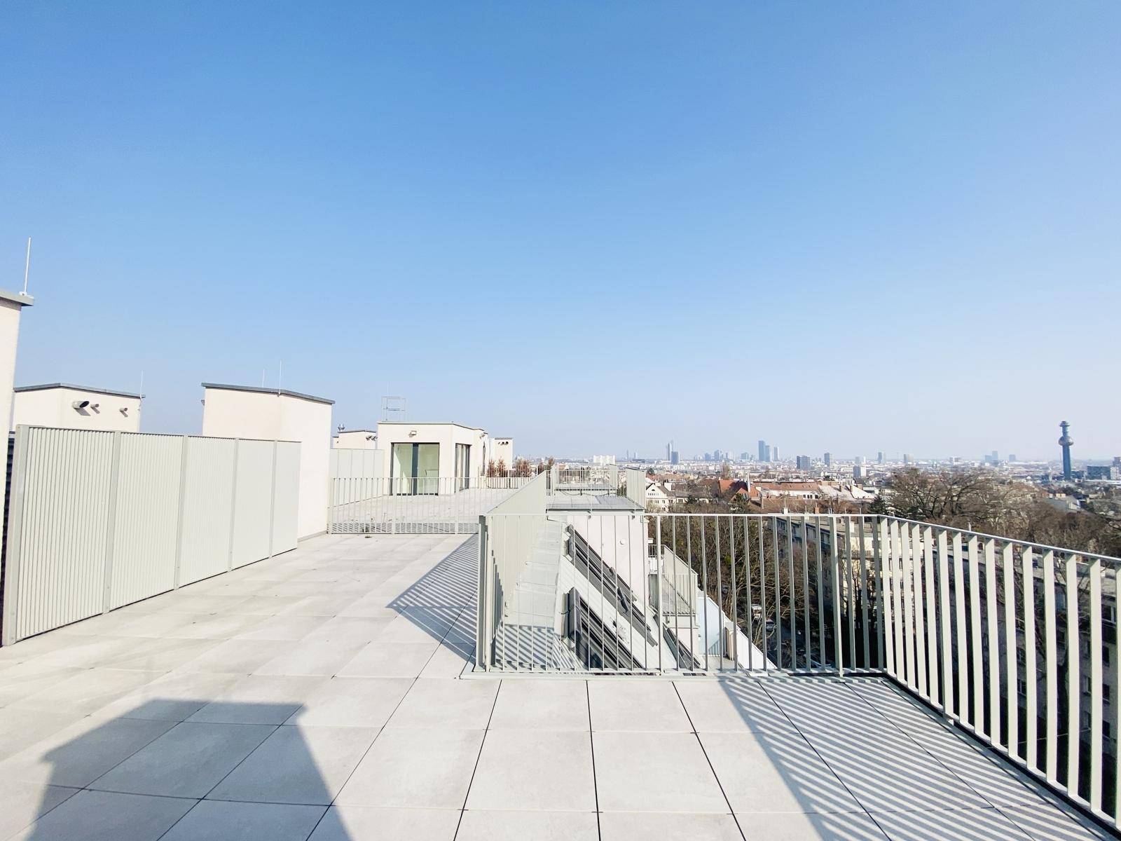 Große Dachterrasse mit Blick auf die Stadt und weitere Gebäude, ideal für Entspannung im Freien.