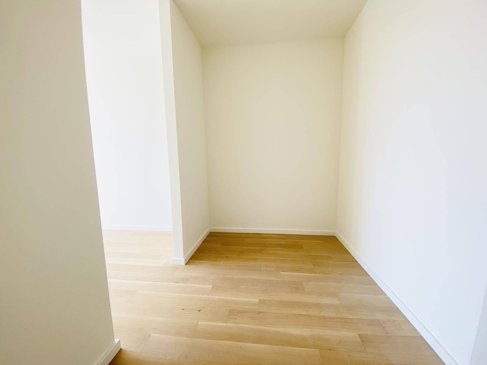 Kleiner, leerer Raum mit Holzboden, ideal als Abstellraum oder begehbarer Kleiderschrank.
