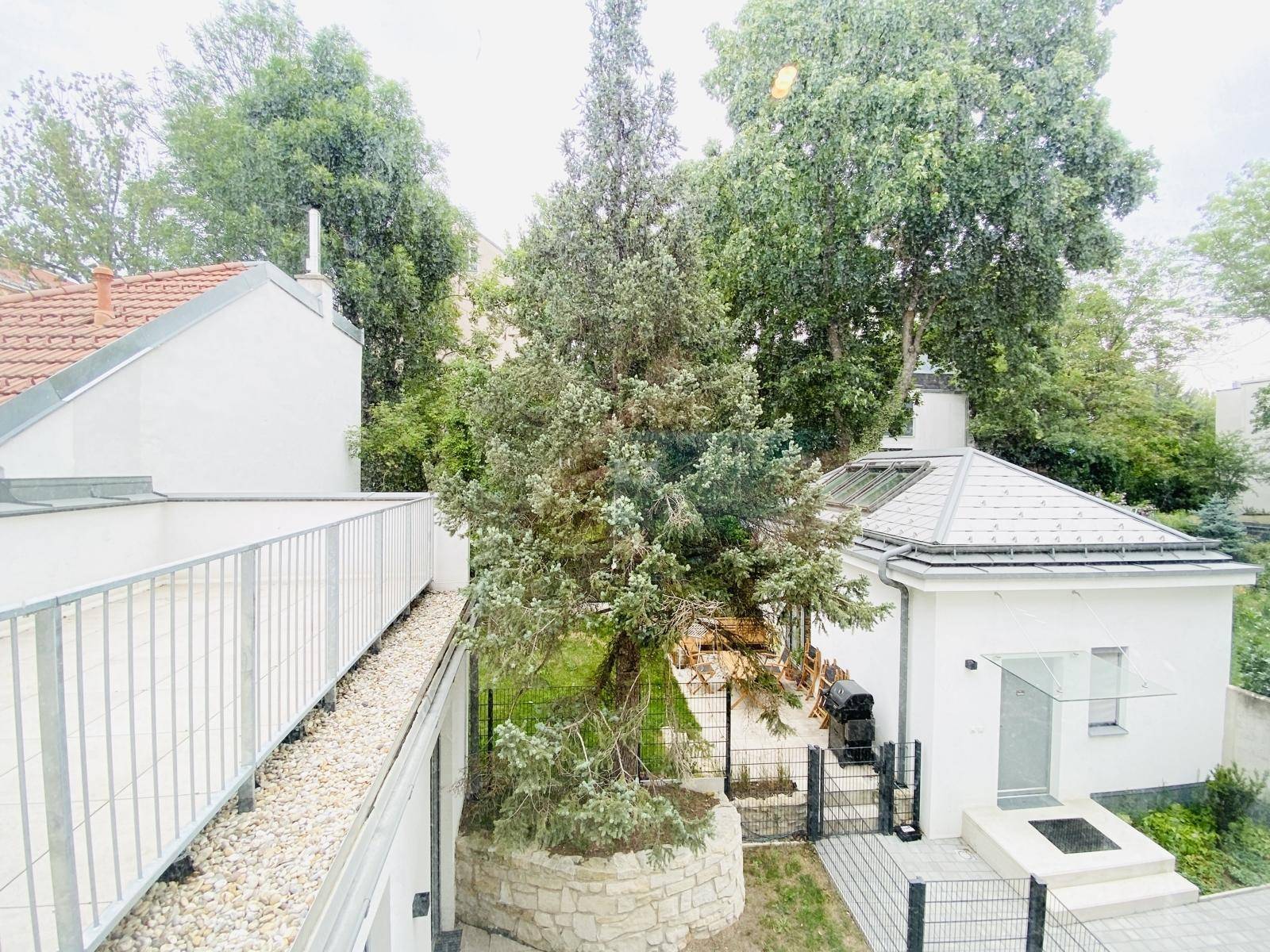 Blick auf einen begrünten Innenhof mit Bäumen und einem kleinen Nebengebäude.