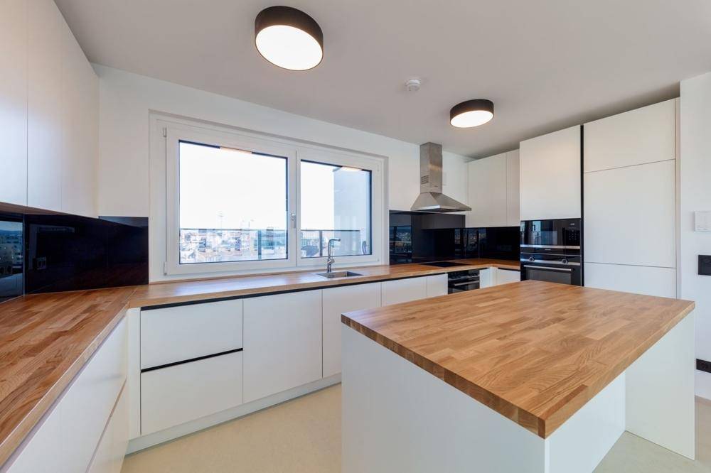 Moderne Küche mit weißen Schränken, Holz-Arbeitsplatten und integrierten Geräten.