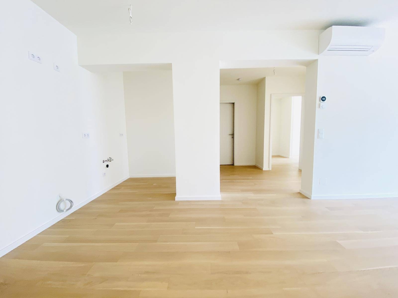 Heller Wohnbereich mit offenem Grundriss, Parkettboden und Vorbereitung für die Küche.