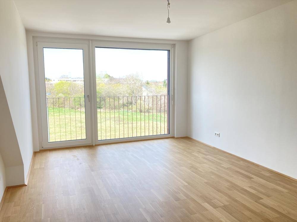 Lichtdurchfluteter Raum mit großem Fenster und Zugang zu einem französischen Balkon.