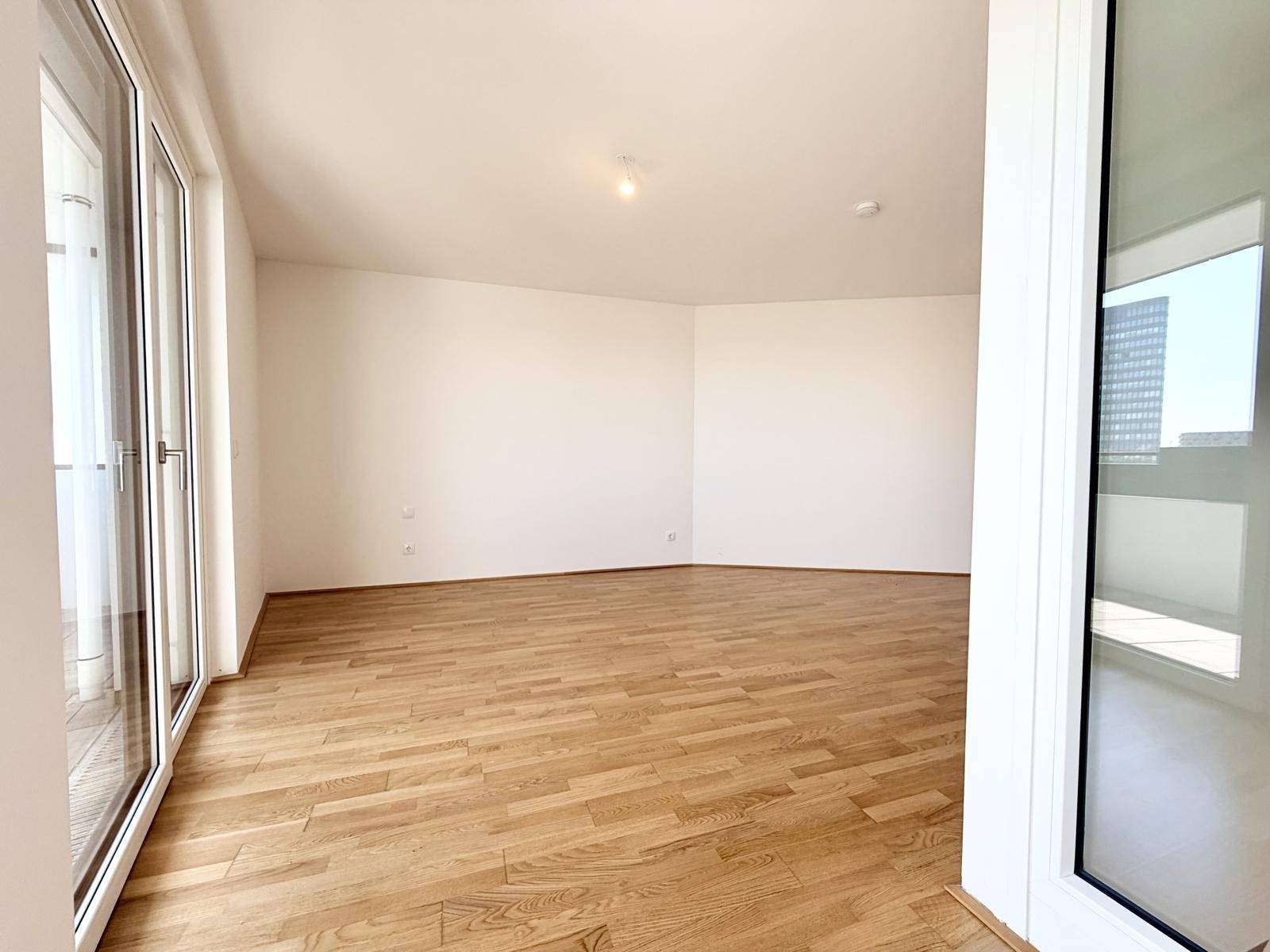 Geräumiger, heller Raum mit Holzboden und großen Fenstern, die viel Licht spenden.