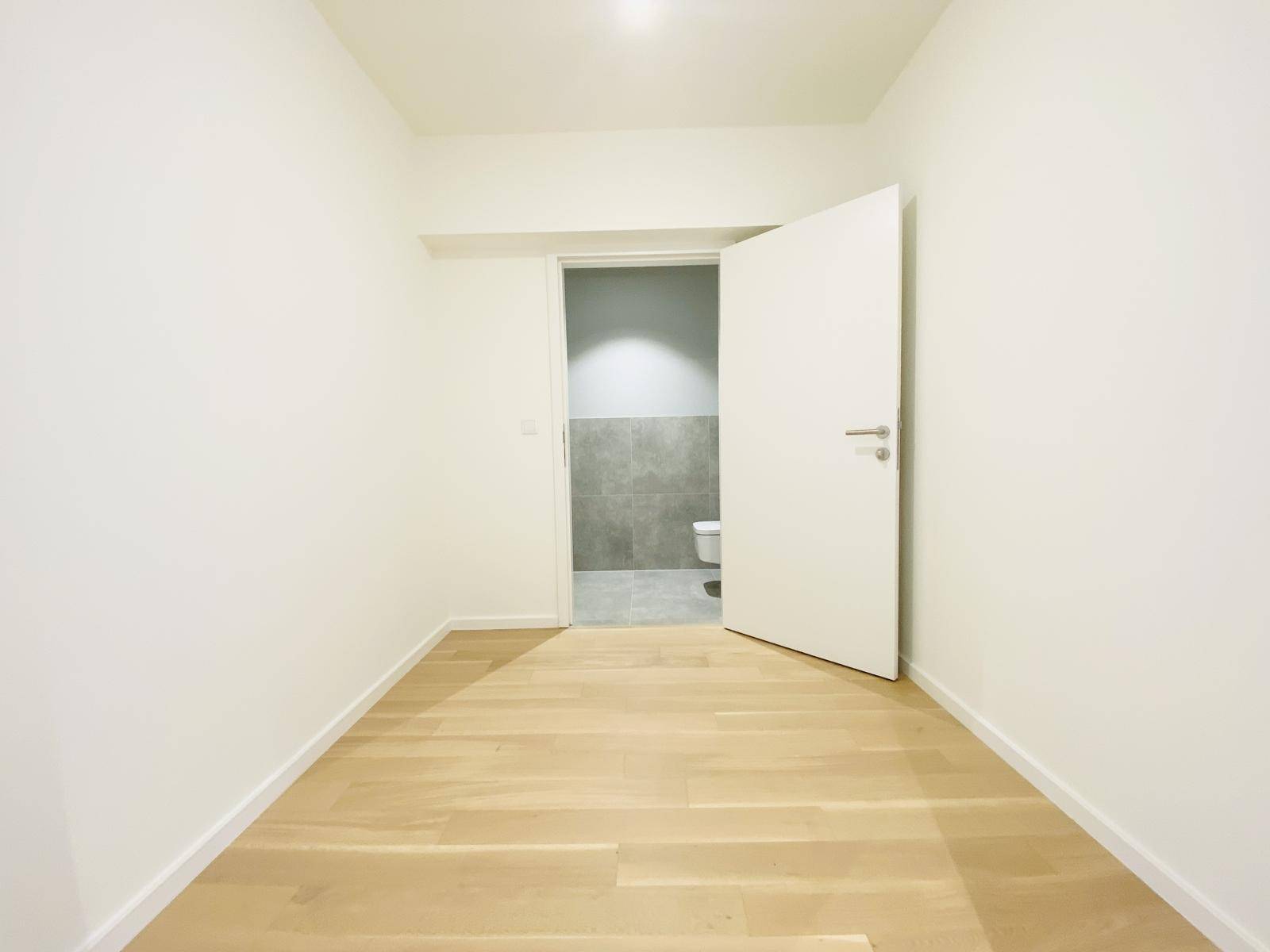 Kleiner Raum mit Holzboden und Zugang zu einem gefliesten Badezimmer oder WC.