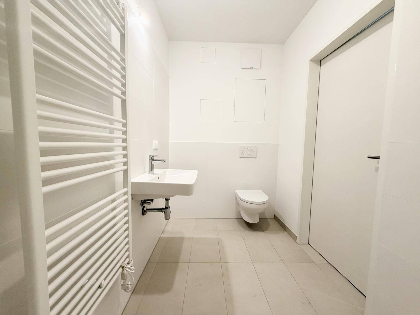Helles Badezimmer mit WC, Waschbecken und modernen Fliesen.