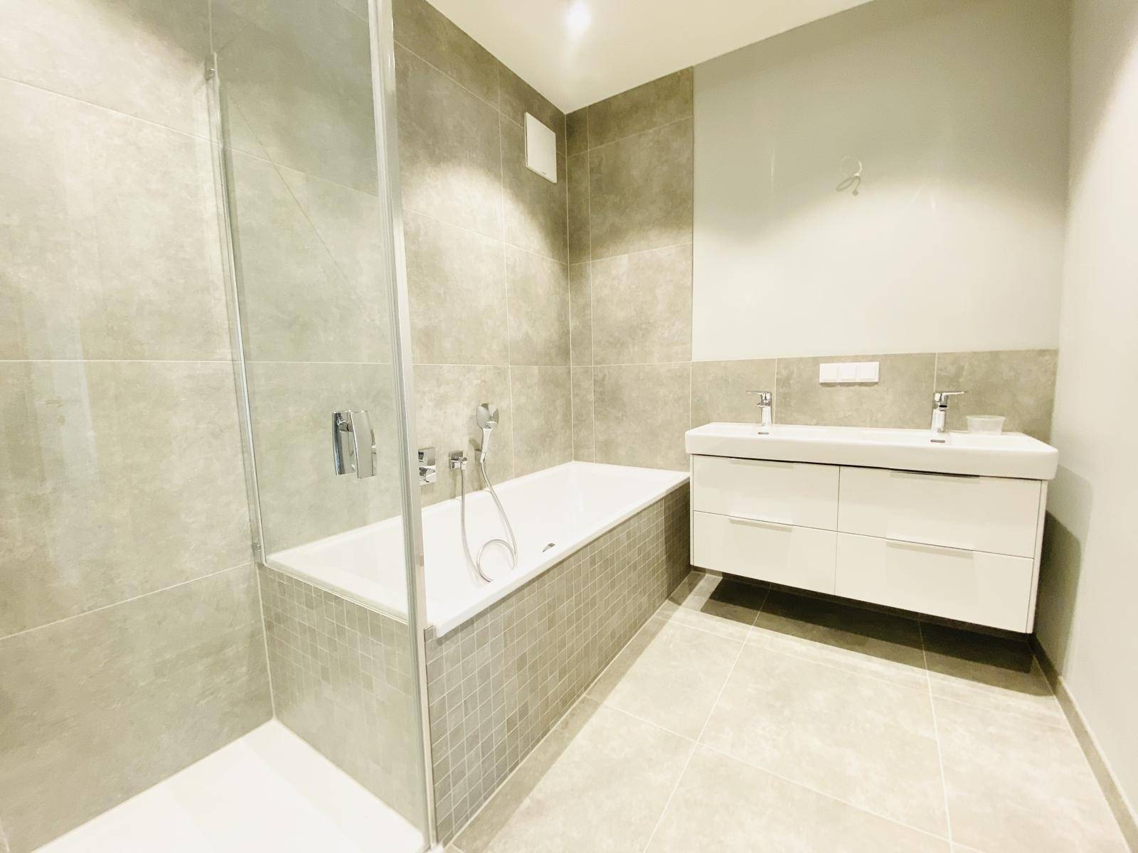 Geräumiges Badezimmer mit Badewanne, Doppelwaschbecken und modernen Fliesen.