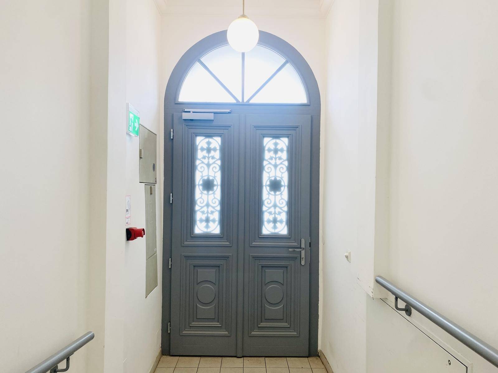 Elegante Eingangstür mit Bogenfenster und dekorativen Glaseinsätzen im Flur.