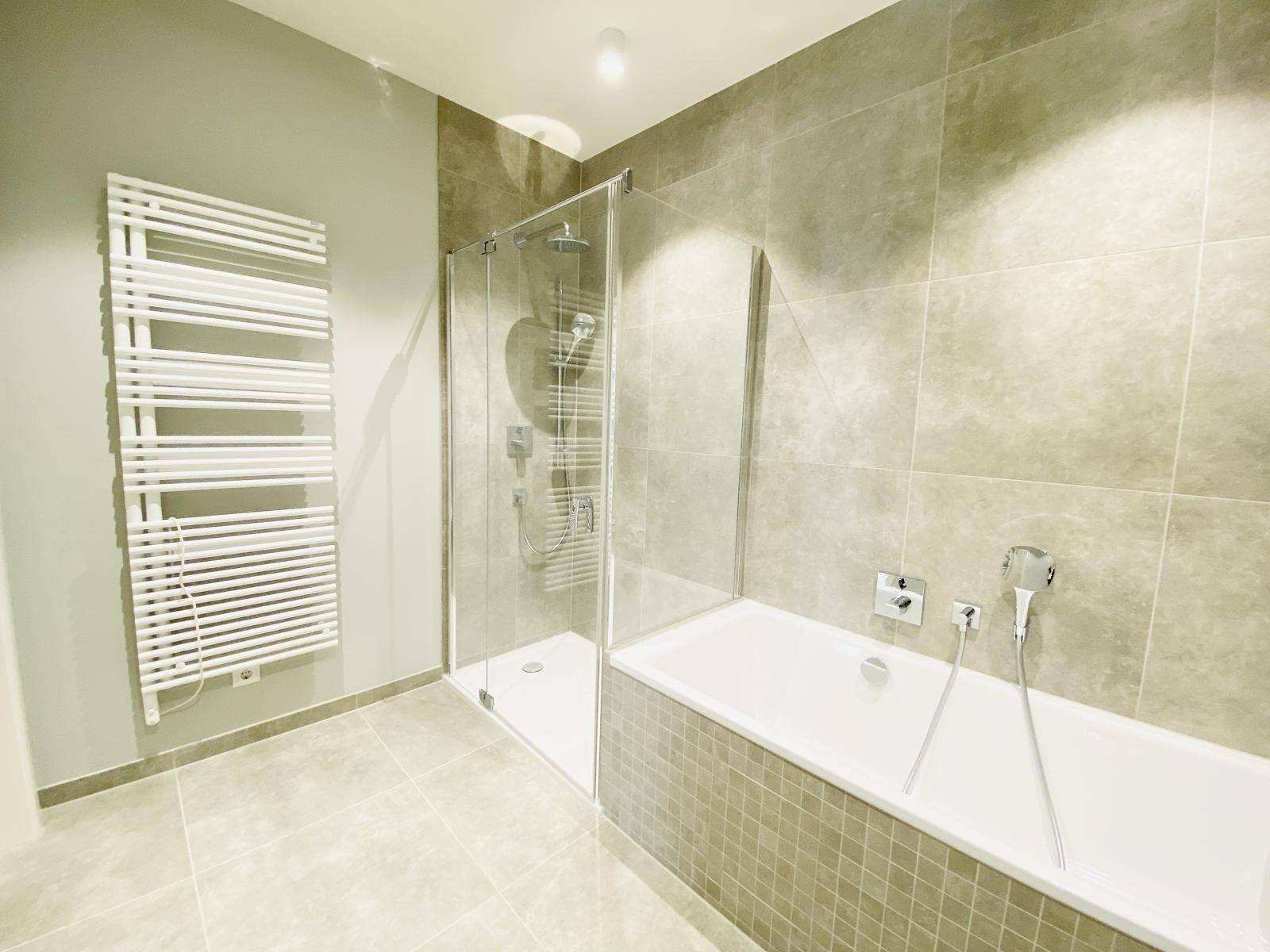 Modernes Badezimmer mit Badewanne, Dusche und beheiztem Handtuchhalter.