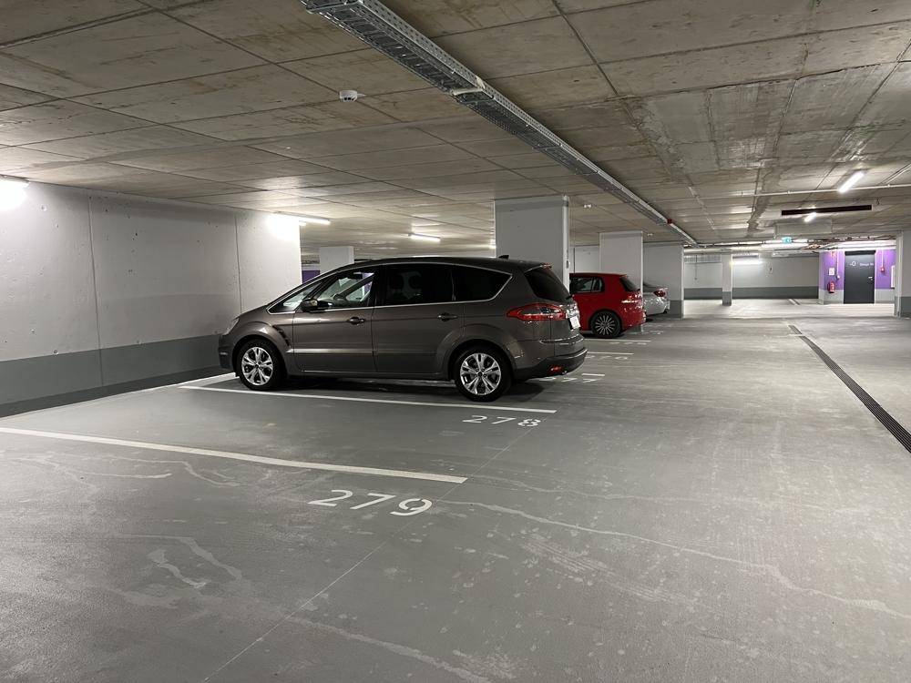 Sauberer Parkbereich in der Tiefgarage mit markierten Stellplätzen und geparkten Autos.