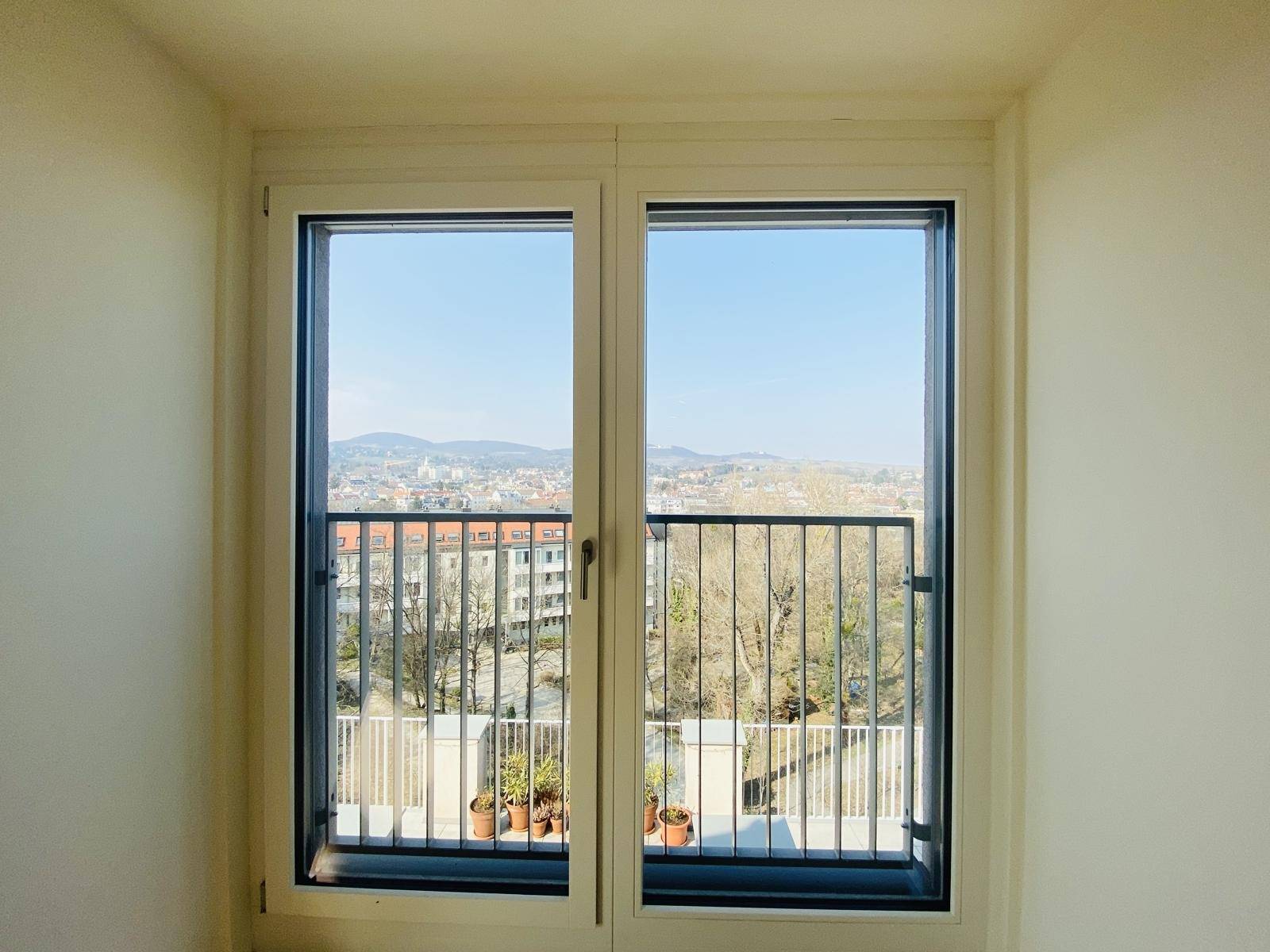 Panoramablick aus dem Zimmer durch große Fenster auf die Stadt und die umliegende Landschaft.