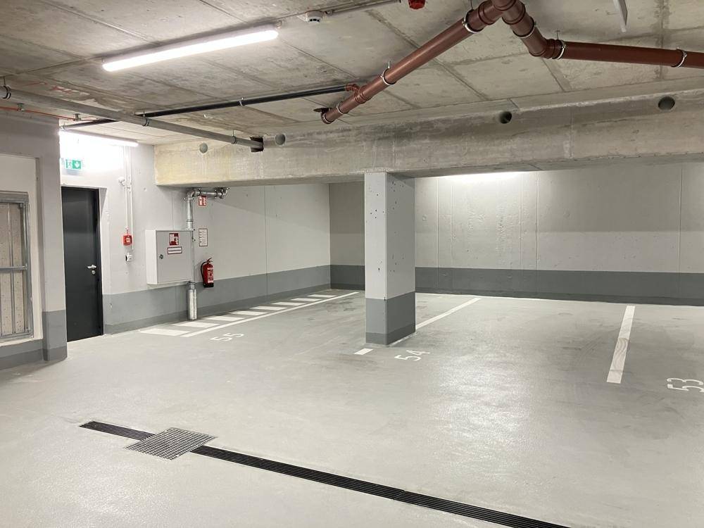 Geräumiger Bereich in der Tiefgarage mit freien Parkplätzen und Notausgang.