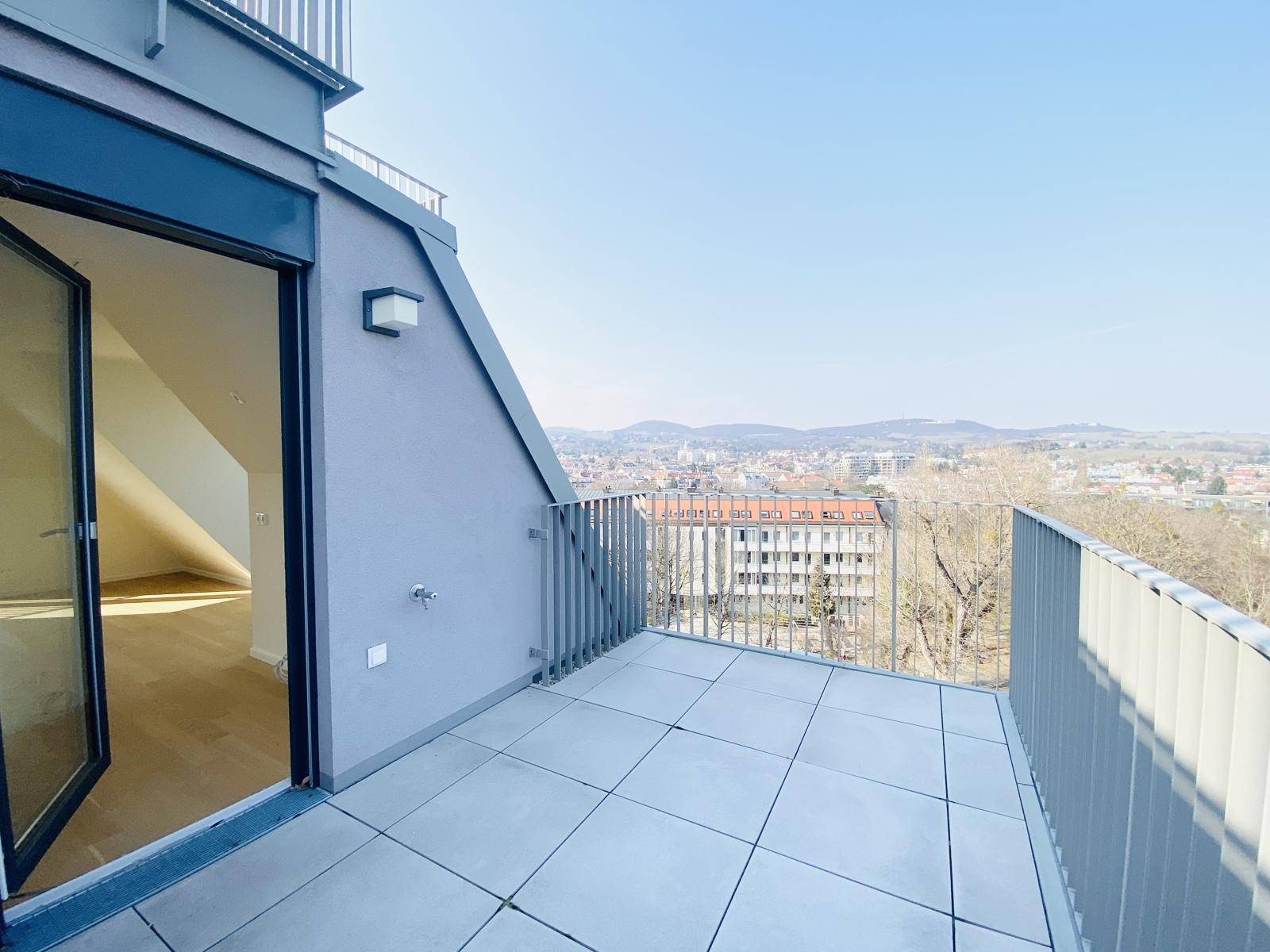 Geräumige Terrasse mit Fliesenboden und Zugang zum Innenbereich, bietet einen weiten Stadtblick.