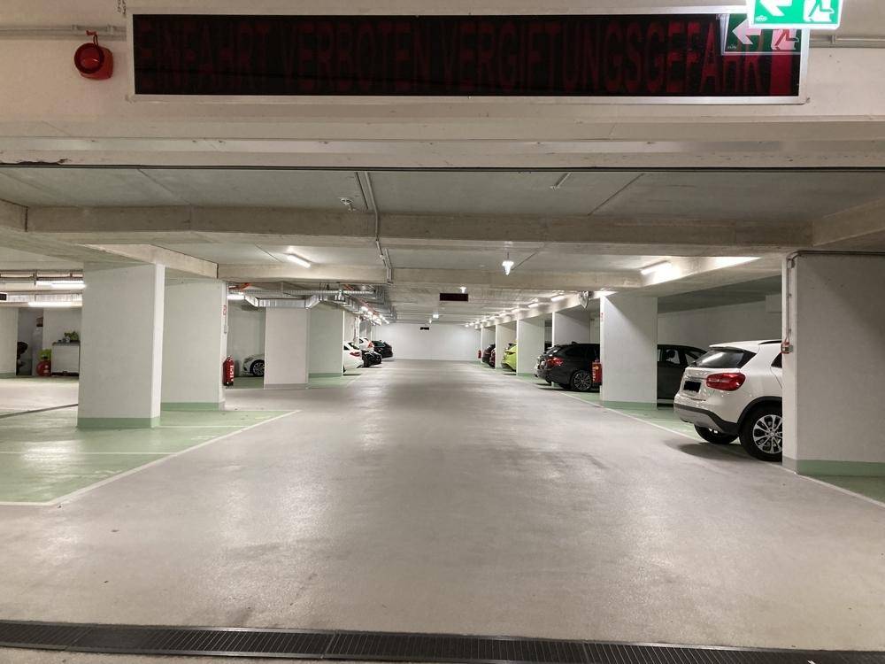 Helle und geräumige Tiefgarage mit zahlreichen Parkplätzen und modernen Leuchten.