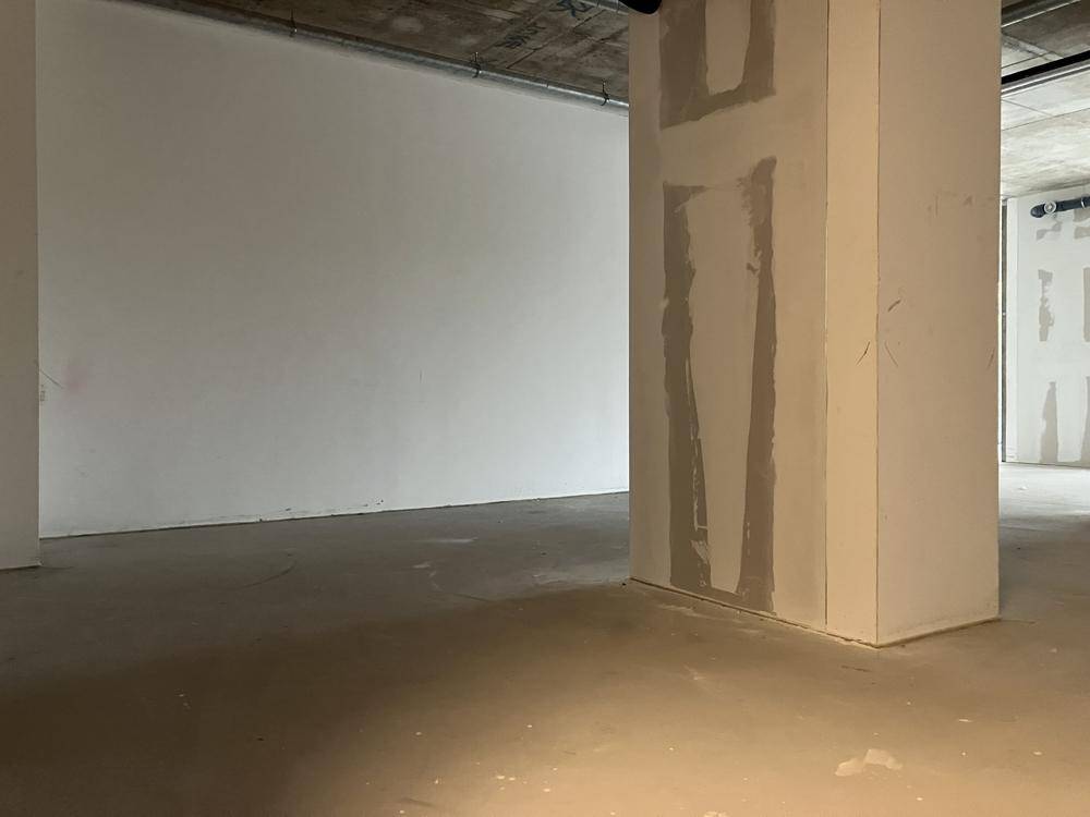 Ecke eines Rohbauraumes mit Betonboden und einer tragenden Säule, bereit für den Innenausbau.