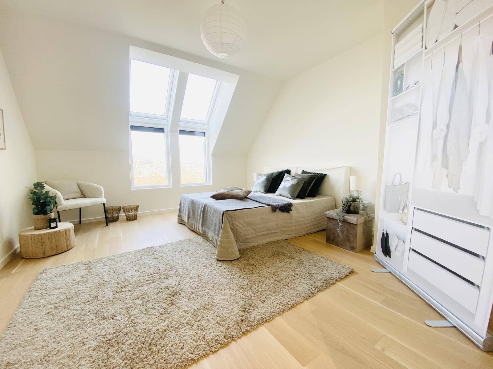 Geräumiges Schlafzimmer im Dachgeschoss mit viel Tageslicht durch große Dachfenster und Holzboden.