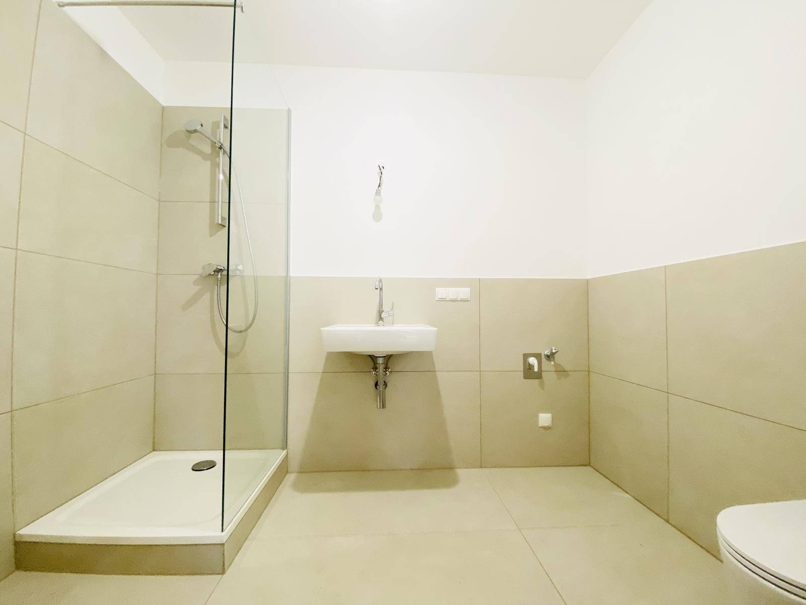 Modernes Badezimmer mit begehbarer Dusche, Waschbecken und hellen Fliesen.