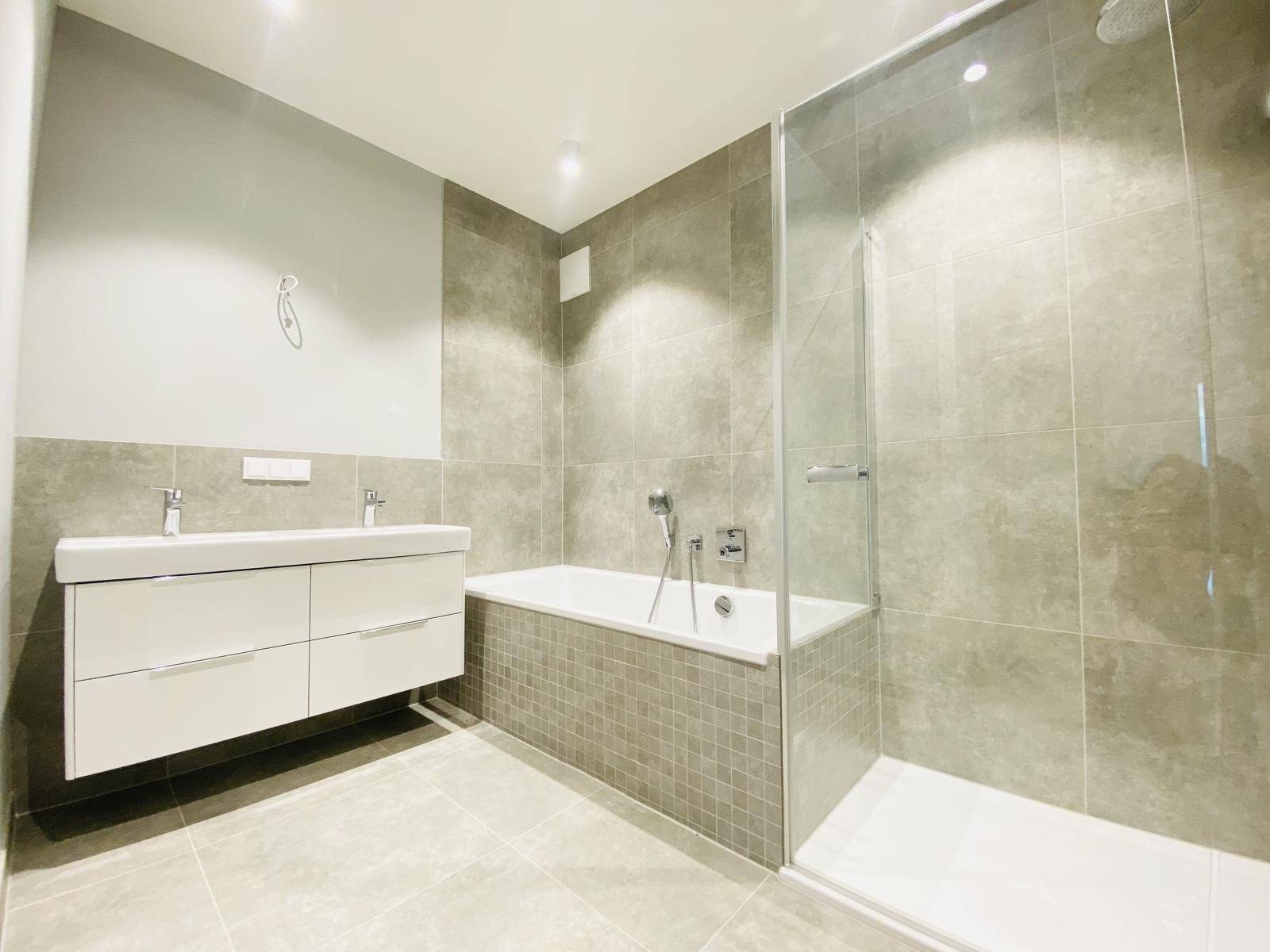 Modernes Badezimmer mit Doppelwaschbecken, Badewanne und separater Glasdusche.