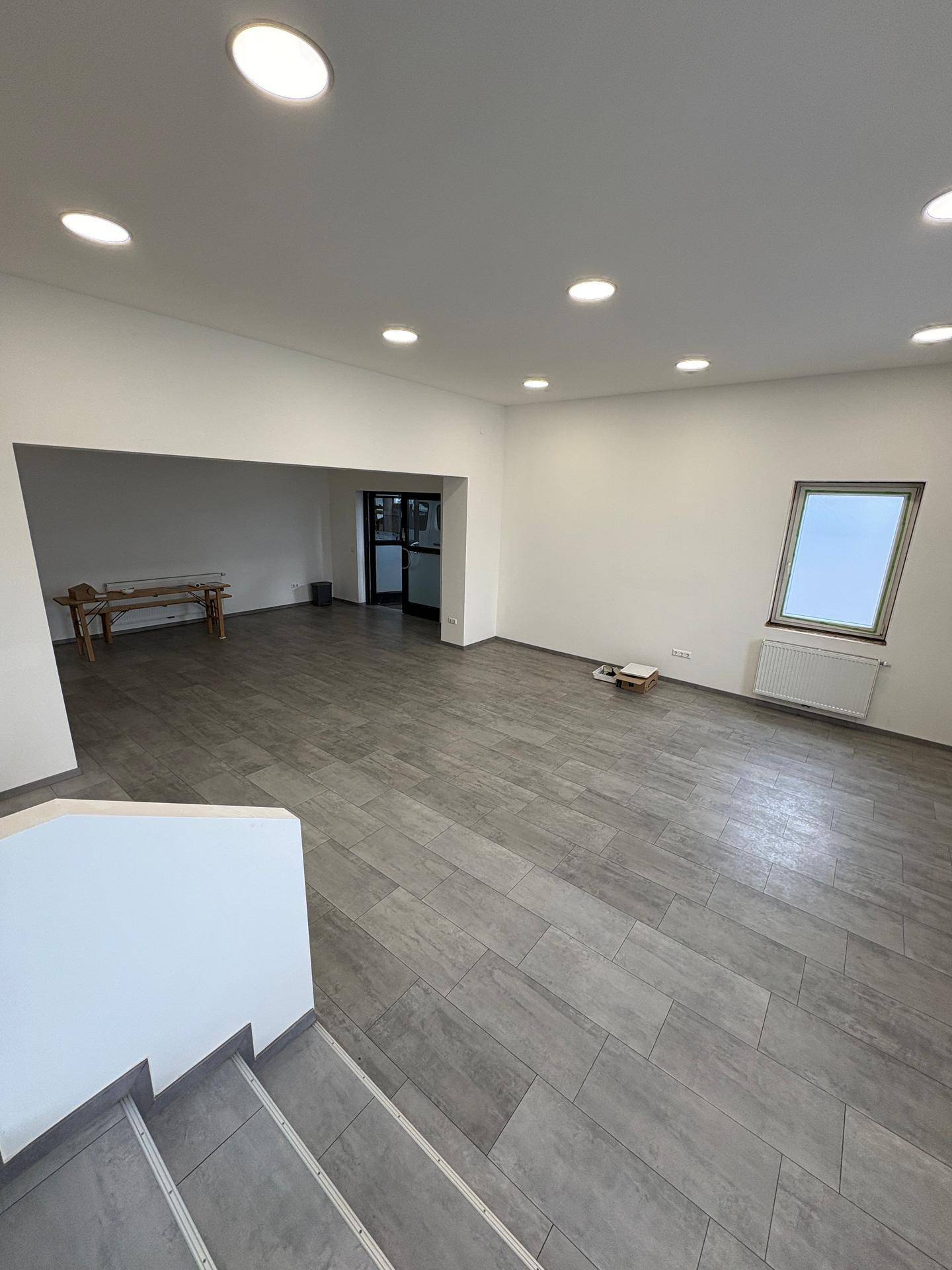Geräumiger Gewerberaum mit großen Fenstern, Einbaustrahlern und modernen Fliesenboden.