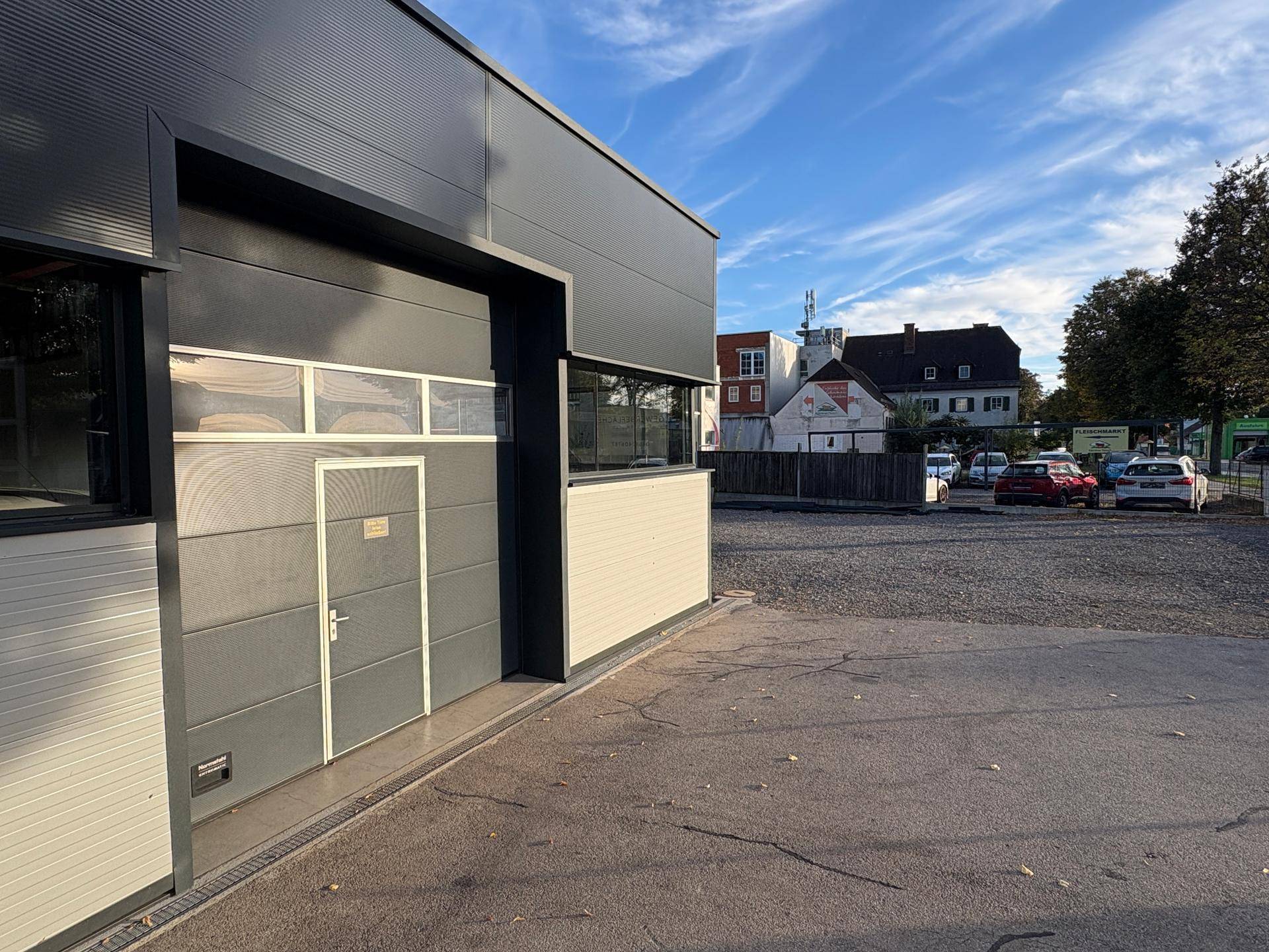 Außenansicht des Gewerbegebäudes mit großem Parkplatz und Blick auf die Umgebung.