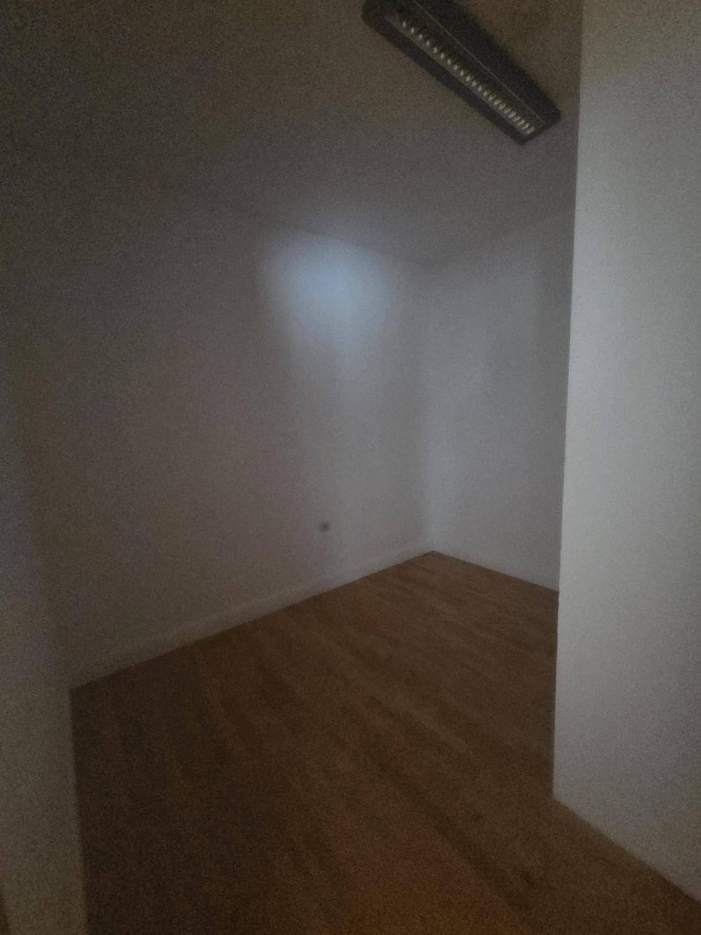Leerer Raum mit Holzboden und wenig natürlichem Licht.