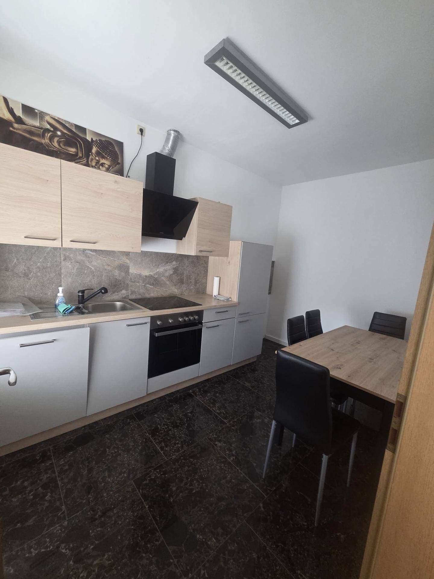 Gut ausgestattete Küche mit dunklem Fliesenboden, Essbereich und modernen Geräten.
