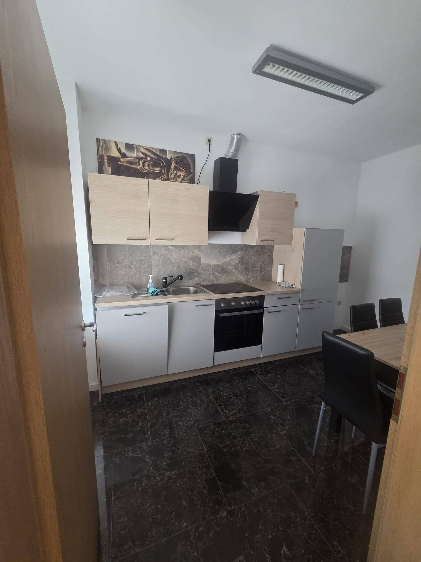 Moderne Küche mit dunklem Fliesenboden, hellen Schränken und Essbereich.