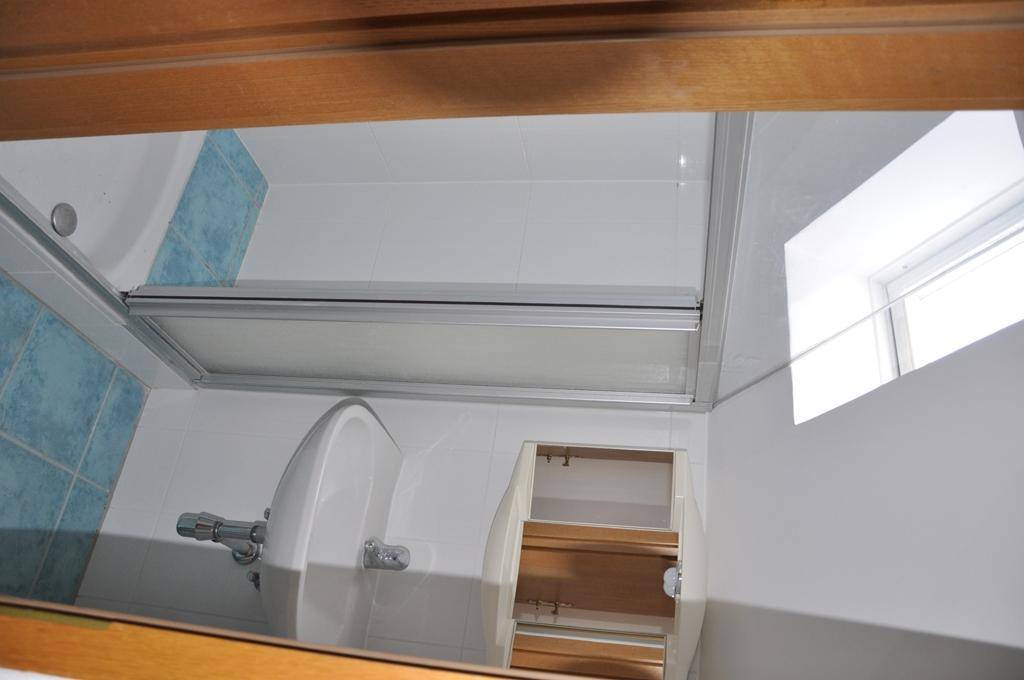 Badezimmer mit weißen und blauen Fliesen, Toilette und einer Duschkabine mit Glastür.