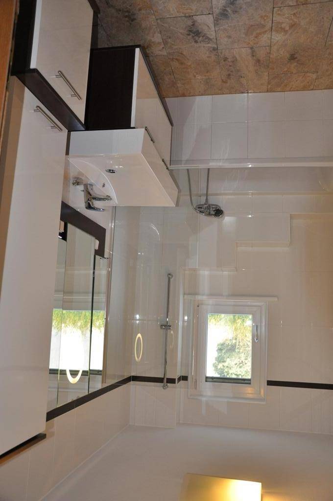 Modernes Badezimmer mit Steinwandfliesen, weißer Einrichtung und begehbarer Dusche.