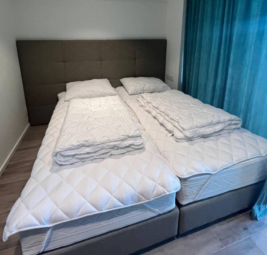 Helles Schlafzimmer mit zwei Einzelbetten und modernem Holzboden.