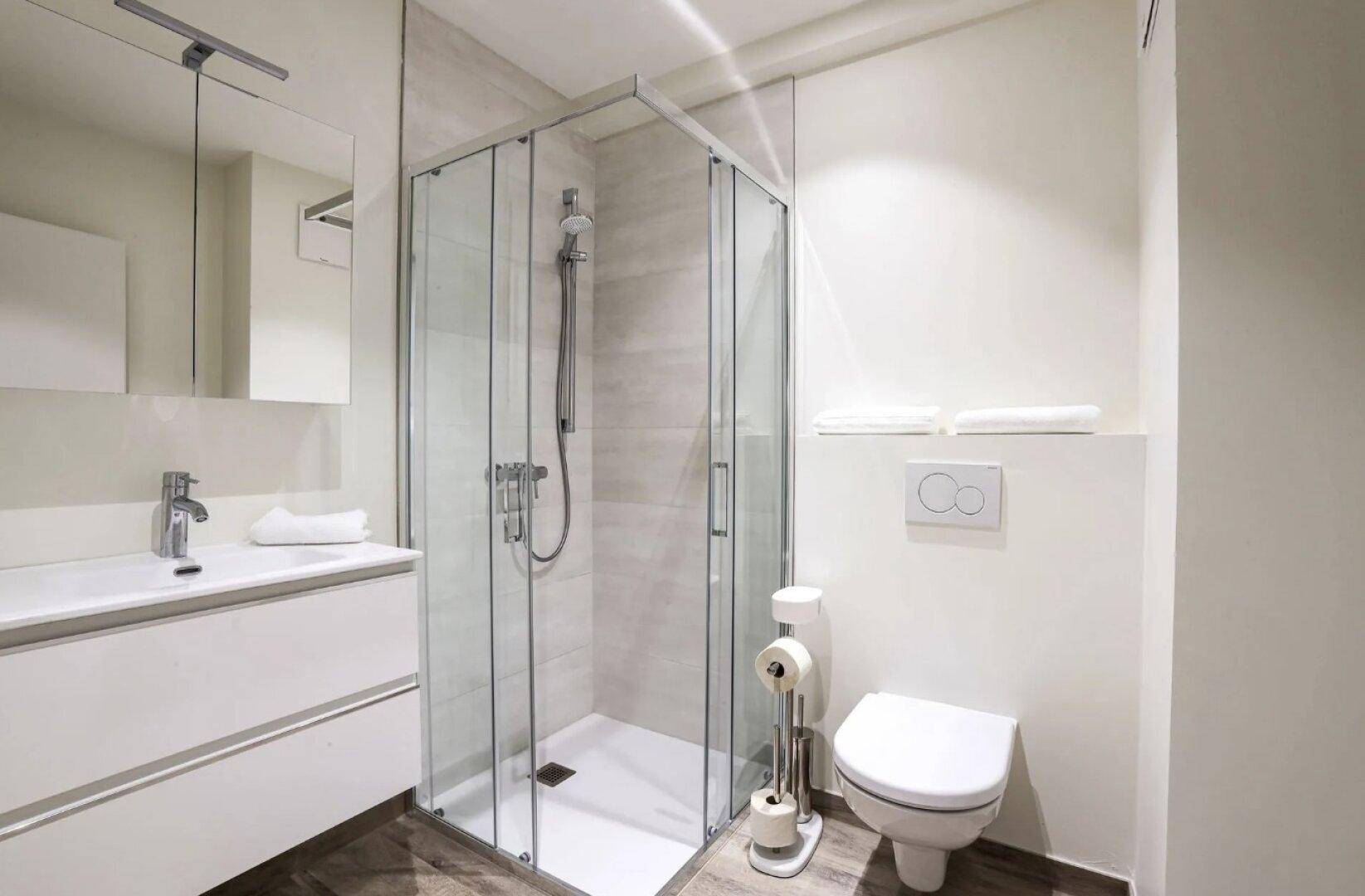 Modernes Badezimmer mit begehbarer Dusche, weißem Waschtisch und Wand-WC.