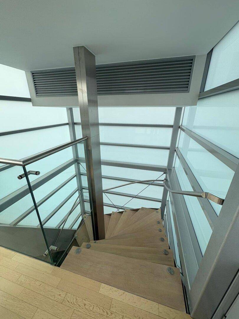 Moderne Treppe mit Holzstufen, Glasgeländer und viel natürlichem Licht.