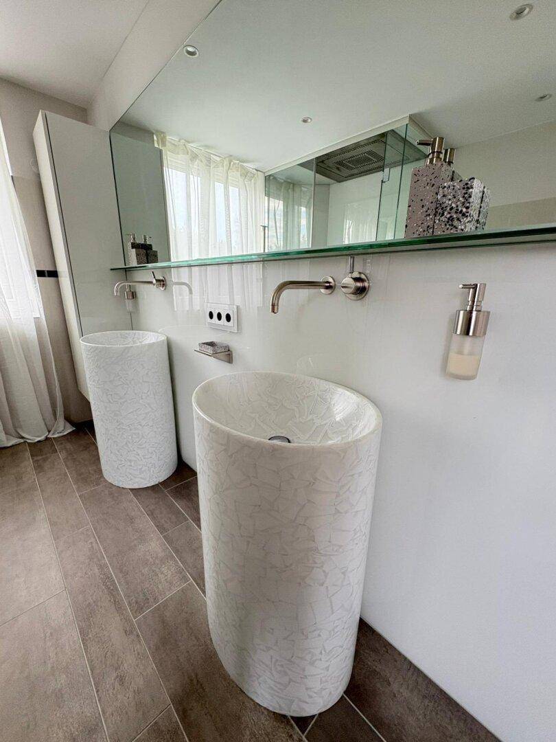 Modernes Badezimmer mit zwei einzigartigen Säulenwaschbecken und großem Spiegel.