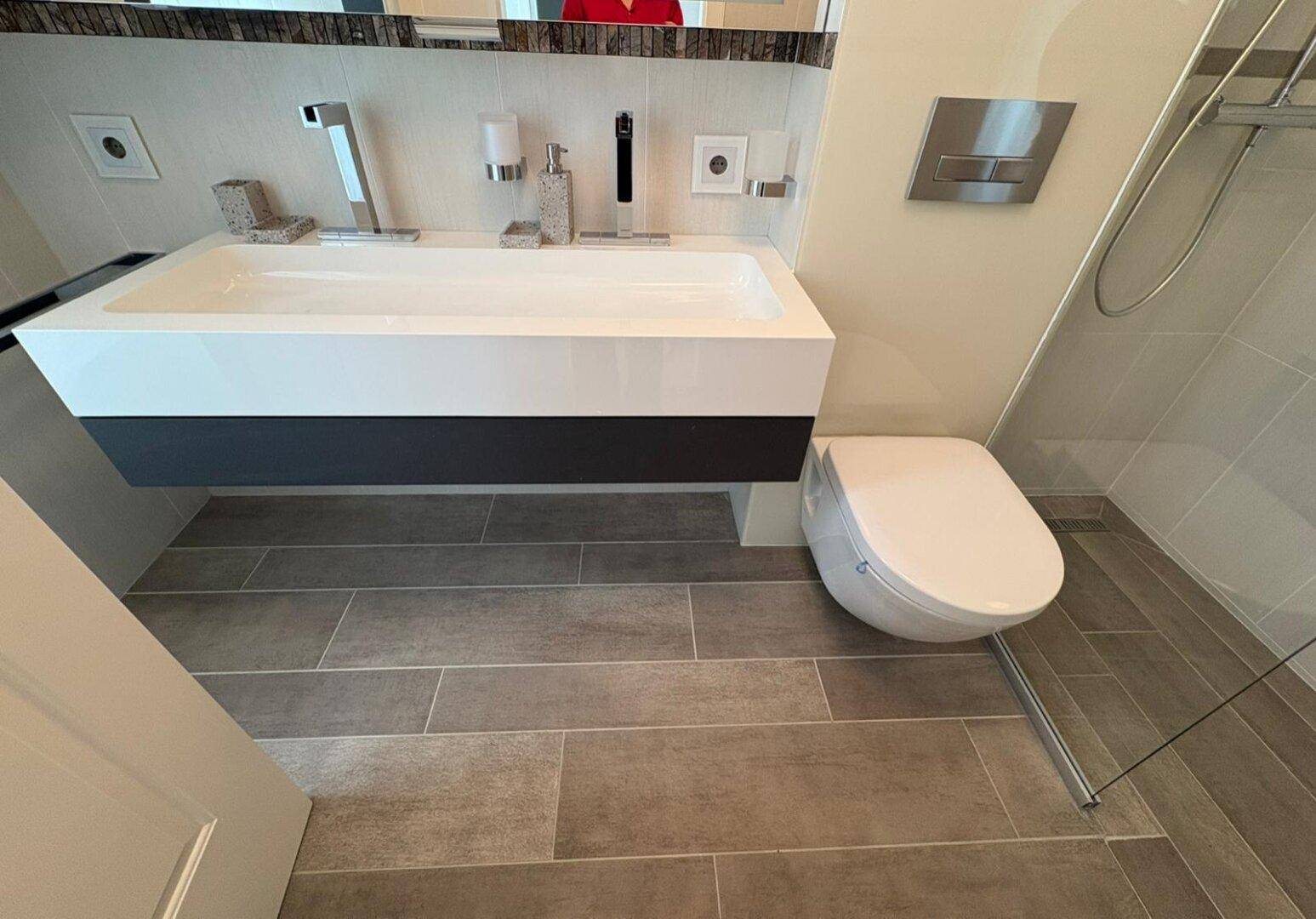 Modernes Badezimmer mit wandhängendem WC, elegantem Waschtisch und Dusche.