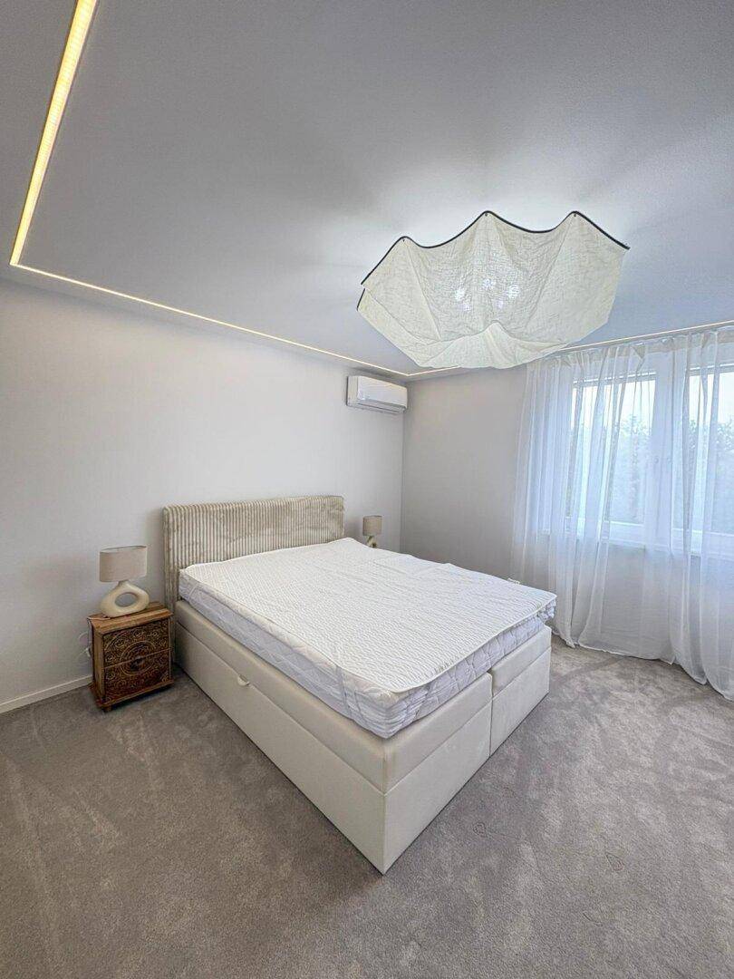 Helles Schlafzimmer mit komfortablem Bett, Einbauschrank und indirekter Beleuchtung.