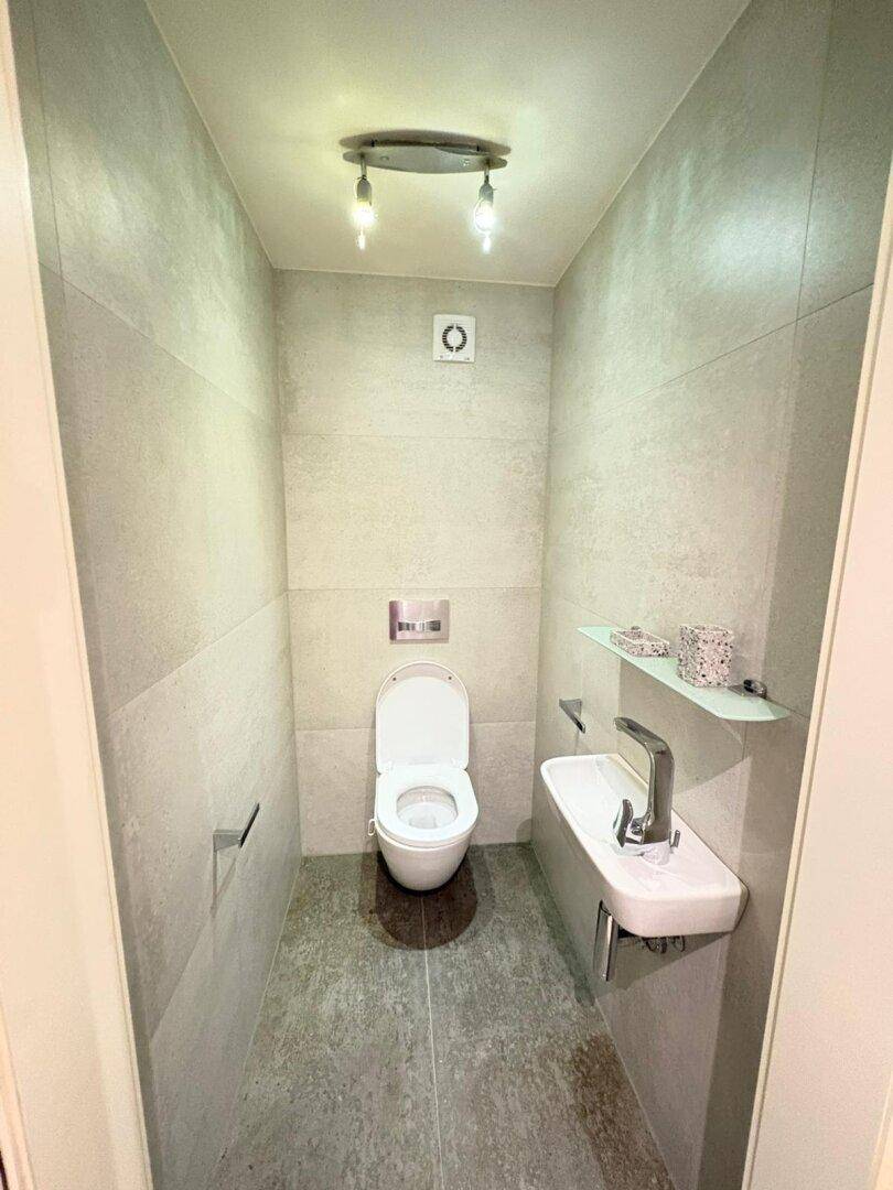 Kompaktes Gäste-WC mit modernen Armaturen und hellen Fliesen an Wänden und Boden.